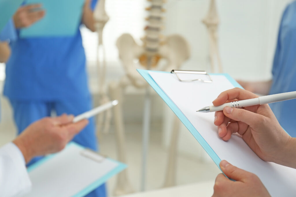 Close-up of three people's hands holding pens and clipboards